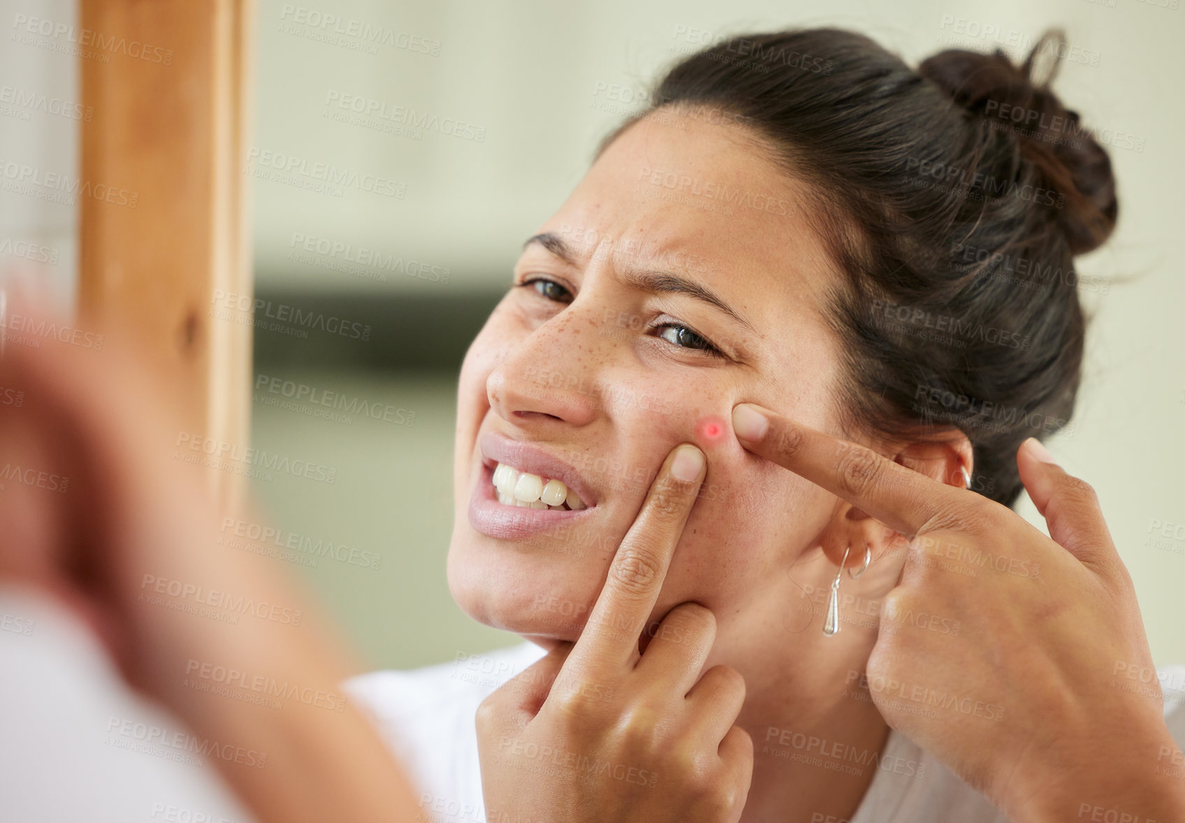 Buy stock photo Shot of a woman squeezing a pimple while looking into the bathroom mirror