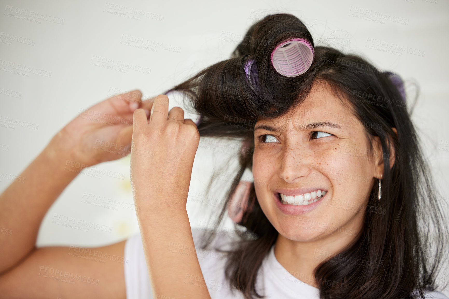 Buy stock photo Shot of a young woman taking rollers out of her hair