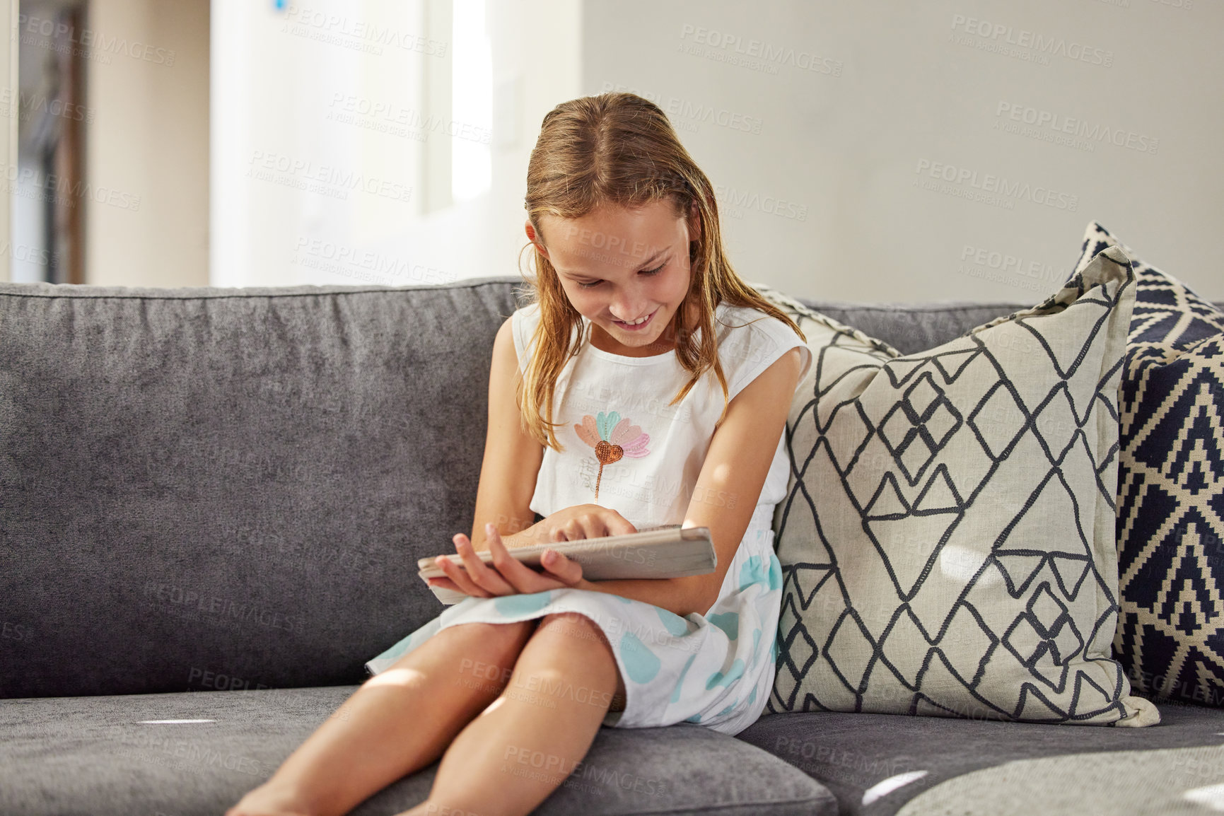 Buy stock photo Happy, home and girl on couch, tablet and typing for games, social media and online cartoon. Apartment, child development or kid with tech, internet or digital app with network, smile or reading book