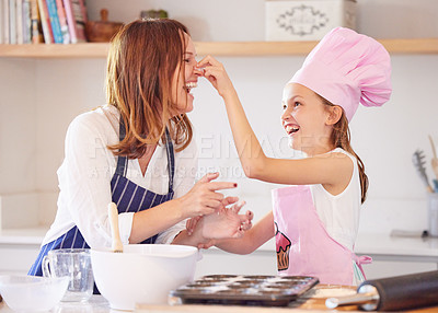 Buy stock photo Shot of an attractive young mother bonding with her daughter in the kitchen at home while baking