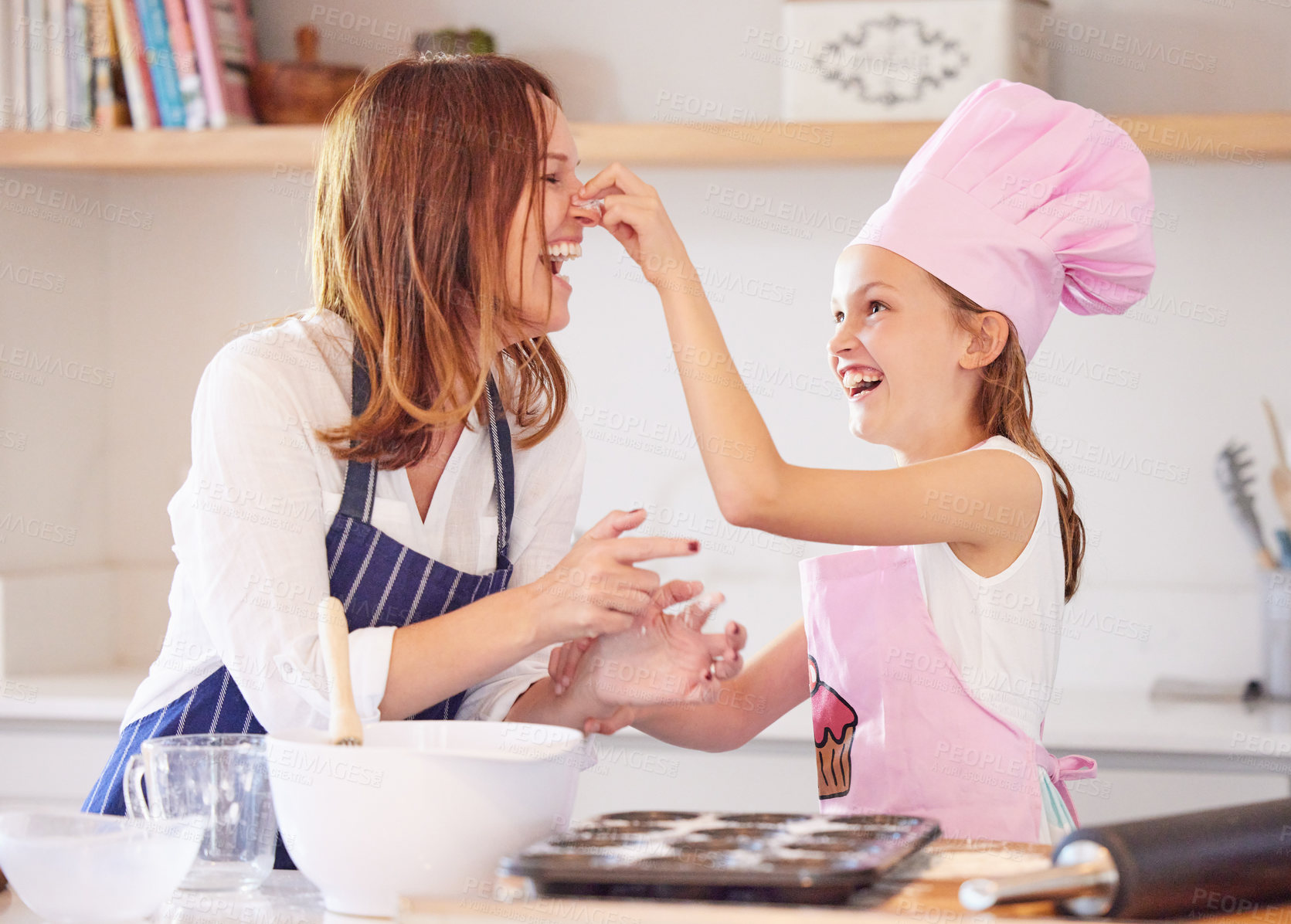 Buy stock photo Shot of an attractive young mother bonding with her daughter in the kitchen at home while baking