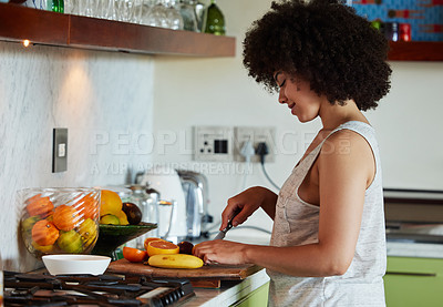 Buy stock photo Shot of a young beautiful woman slicing fruit in the kitchen at home