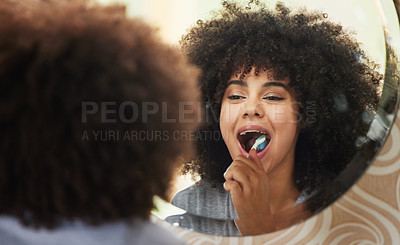 Buy stock photo Shot of an attractive young woman looking in the mirror while brushing her teeth at home