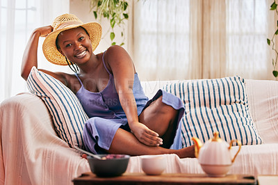 Buy stock photo Portrait of a young beautiful woman wearing a sunhat while relaxing on the sofa at home