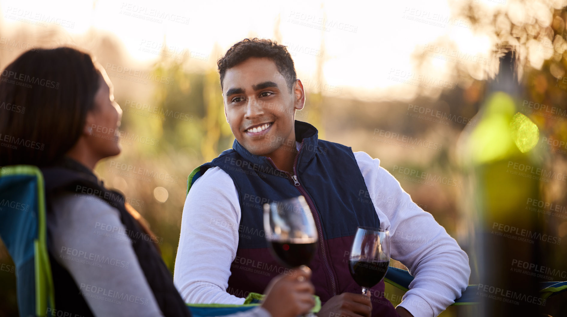 Buy stock photo Shot of a young couple having a glass outside while camping outside