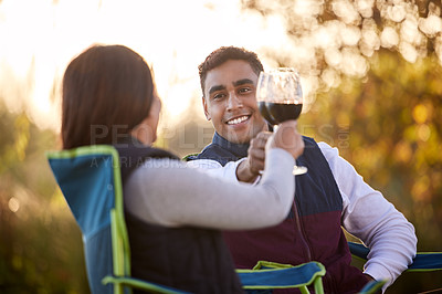 Buy stock photo Camping, wine and happy couple in park for toast of love, holiday vacation and valentines day picnic. Cheers, man and woman with care, smile and chairs on date for anniversary in nature or forest