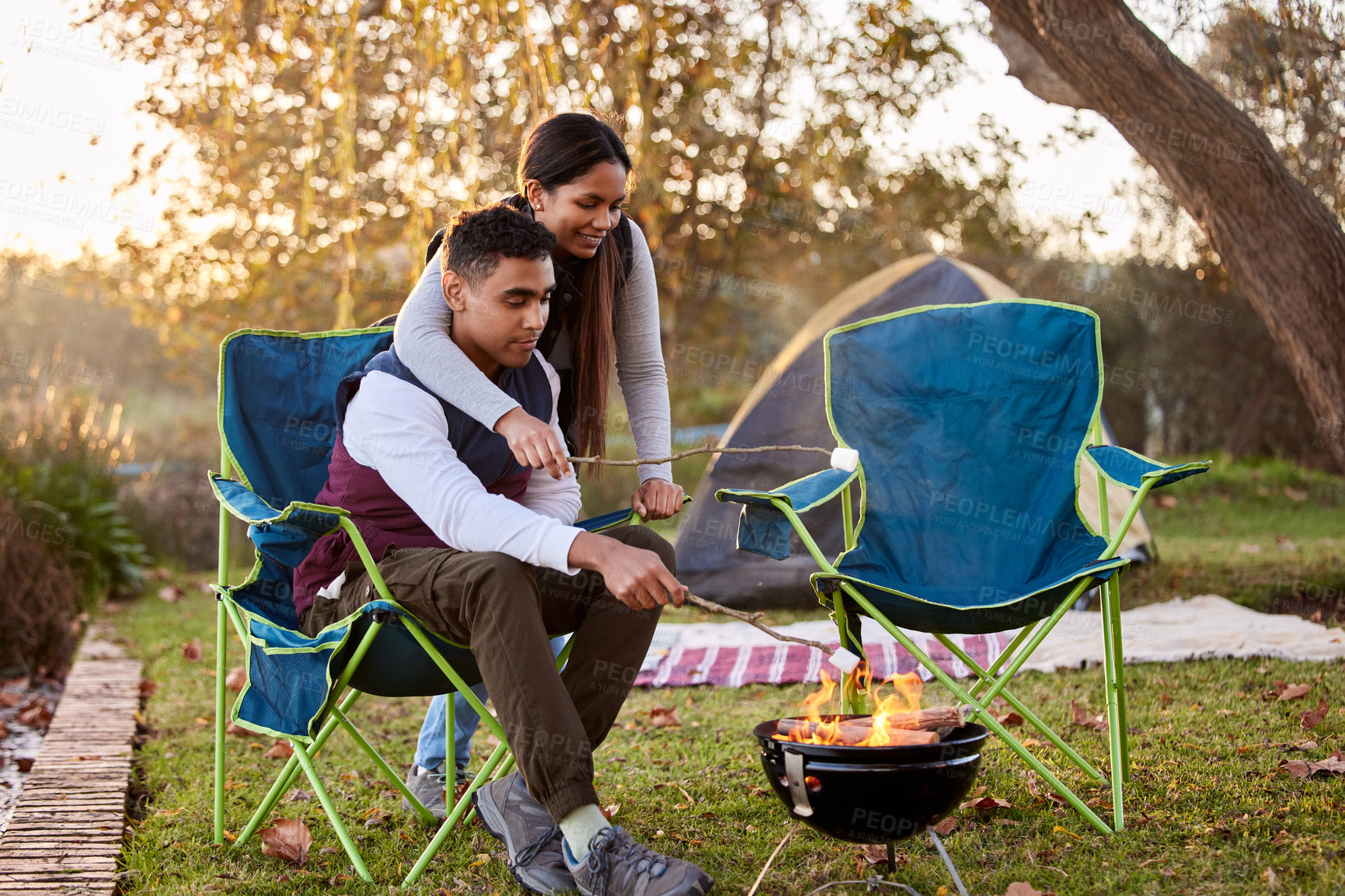 Buy stock photo Fire, camping and couple with marshmallows in nature for romantic vacation, adventure or holiday. Love, happy and young man and woman roasting candy by flame on outdoor weekend trip together.