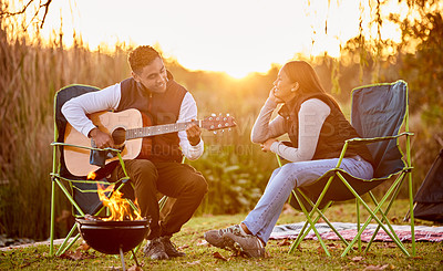 Buy stock photo Shot of a you man playing his guitar to his wife outside while camping