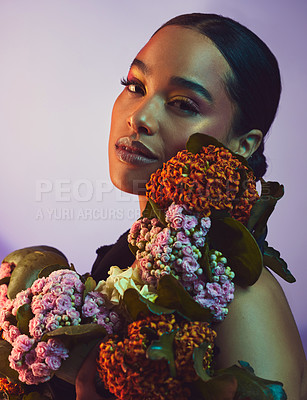 Buy stock photo Studio portrait of an attractive young woman posing with a bouquet against a colourful background