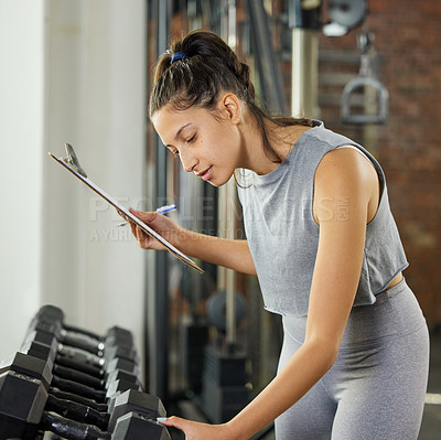 Buy stock photo Shot of a young woman checking the equipment at work in a gym