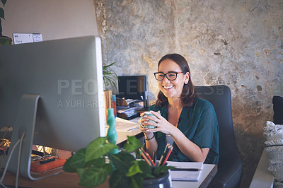 Buy stock photo Shot of a young woman sitting and enjoying a cup of coffee while using her computer to work from home