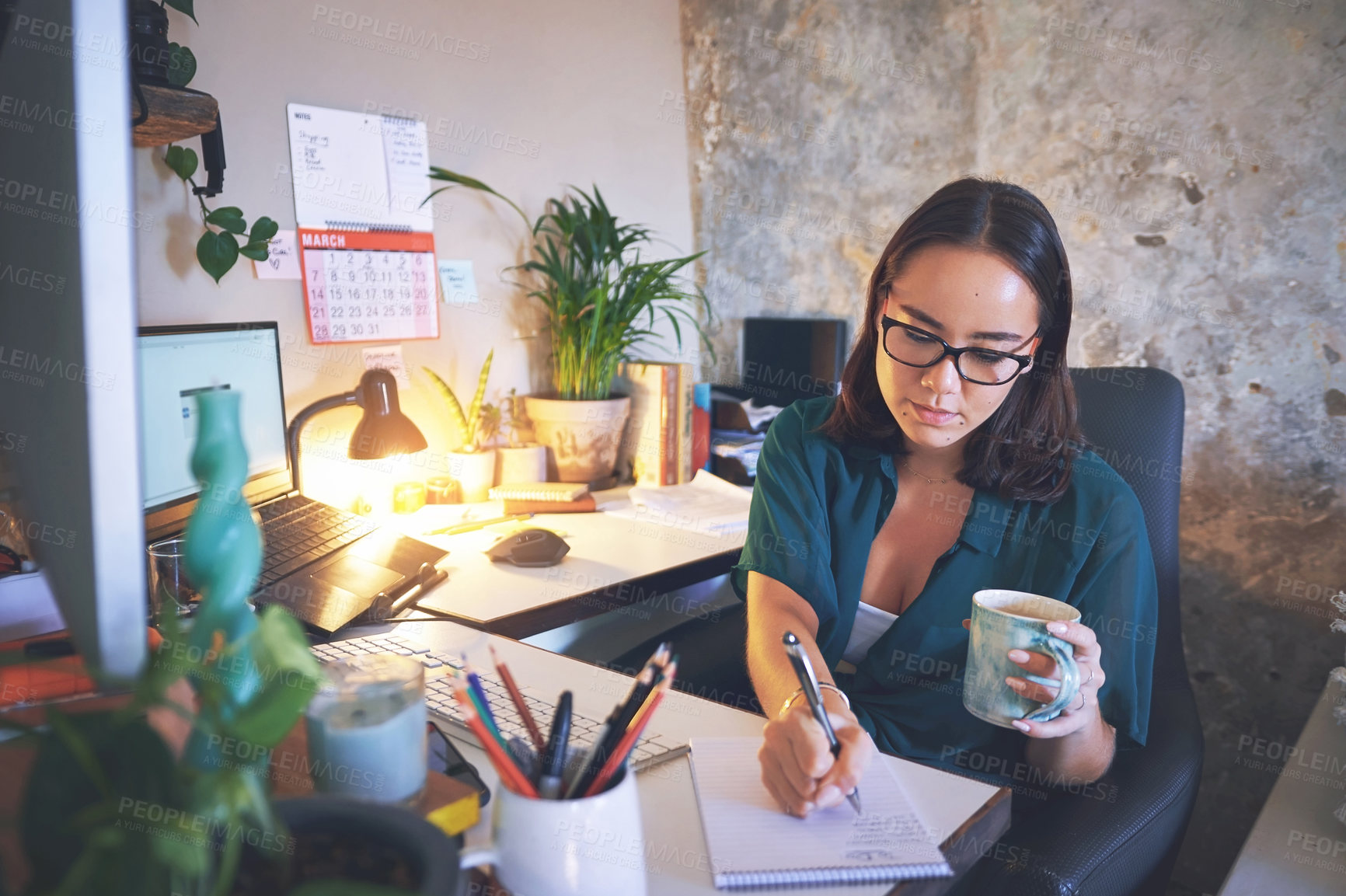 Buy stock photo Shot of an attractive young woman sitting and enjoying a cup of coffee while writing notes in her home office