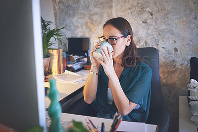 Buy stock photo Shot of a young woman sitting and enjoying a cup of coffee while using her computer to work from home