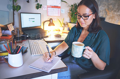 Buy stock photo Shot of an attractive young woman sitting and enjoying a cup of coffee while writing notes in her home office