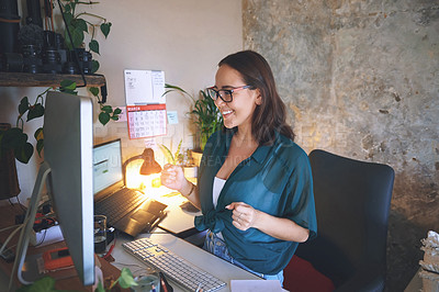 Buy stock photo Shot of an attractive young woman sitting alone and celebrating a success while using her computer to work from home