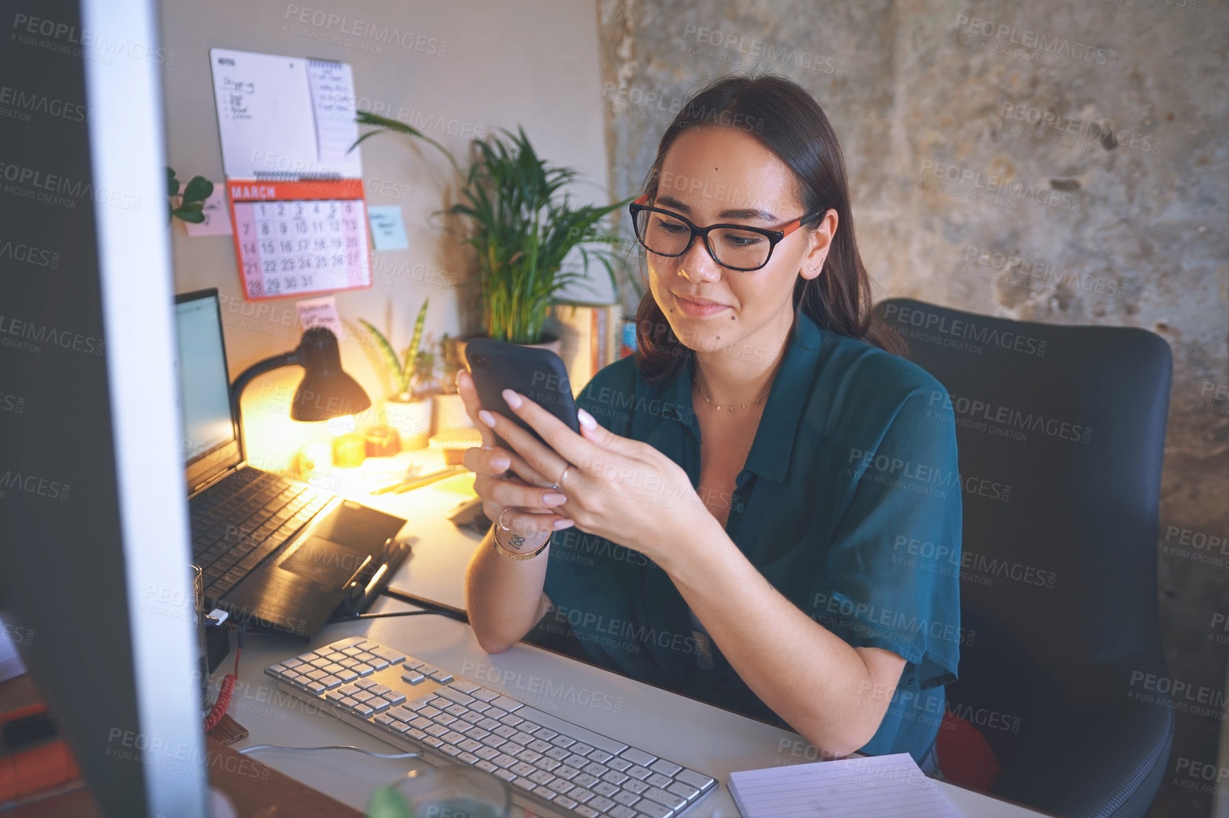 Buy stock photo Shot of an attractive young woman sitting alone and using her cellphone while working from home