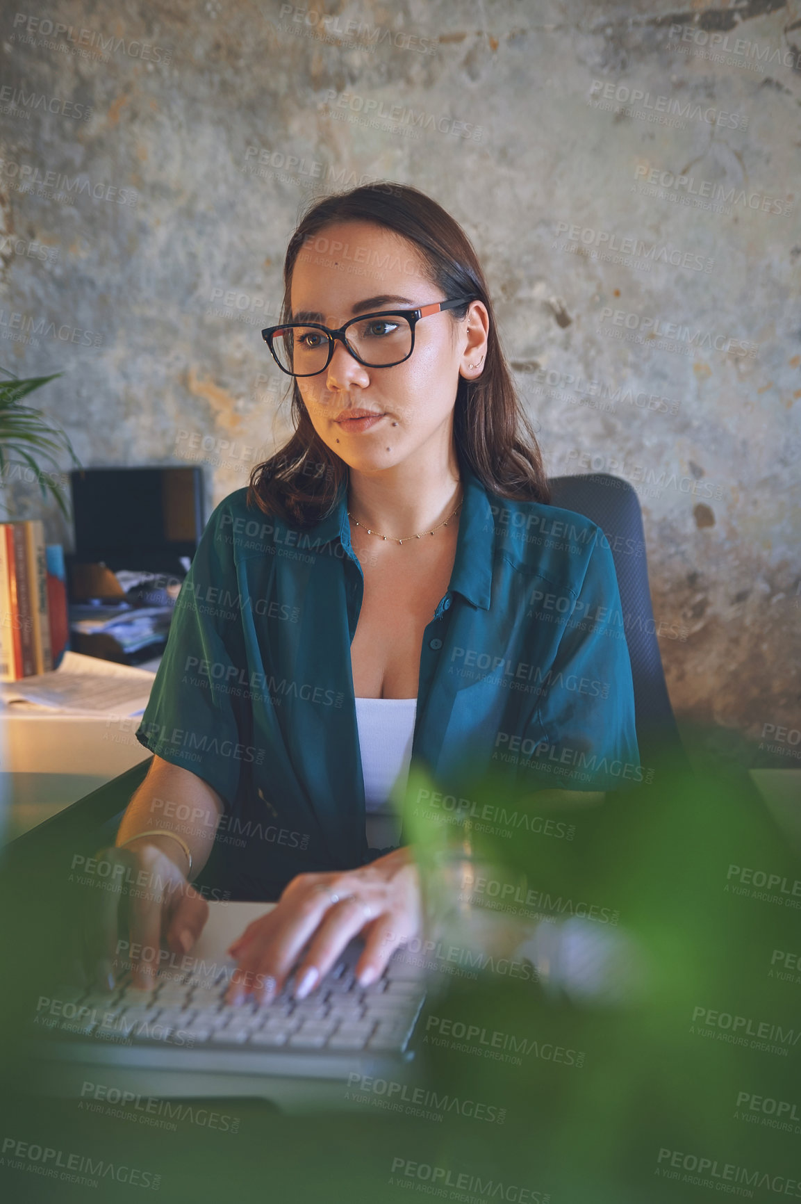 Buy stock photo Shot of an attractive young woman sitting alone and looking contemplative while using her computer to work from home