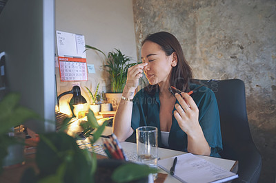 Buy stock photo Shot of an attractive young woman sitting alone and feeling stressed while using her computer to work from home