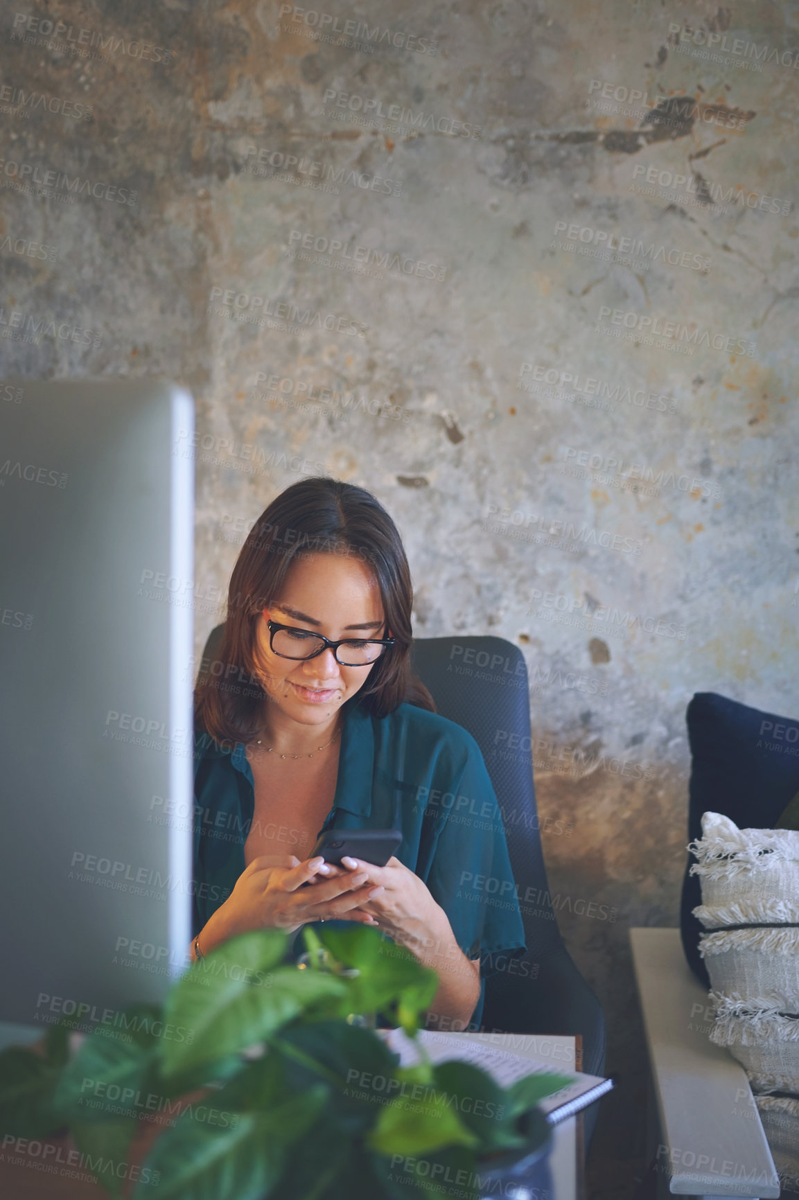 Buy stock photo Shot of an attractive young woman sitting alone and using her cellphone while working from home