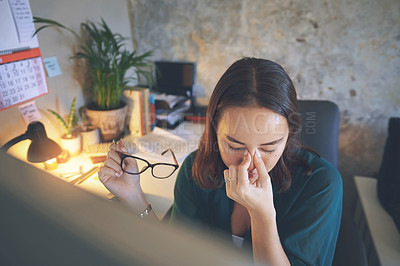 Buy stock photo Shot of an attractive young woman sitting alone and feeling stressed while using her computer to work from home