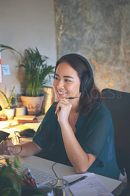 Buy stock photo Shot of an attractive young woman sitting alone and wearing a headset while working from home