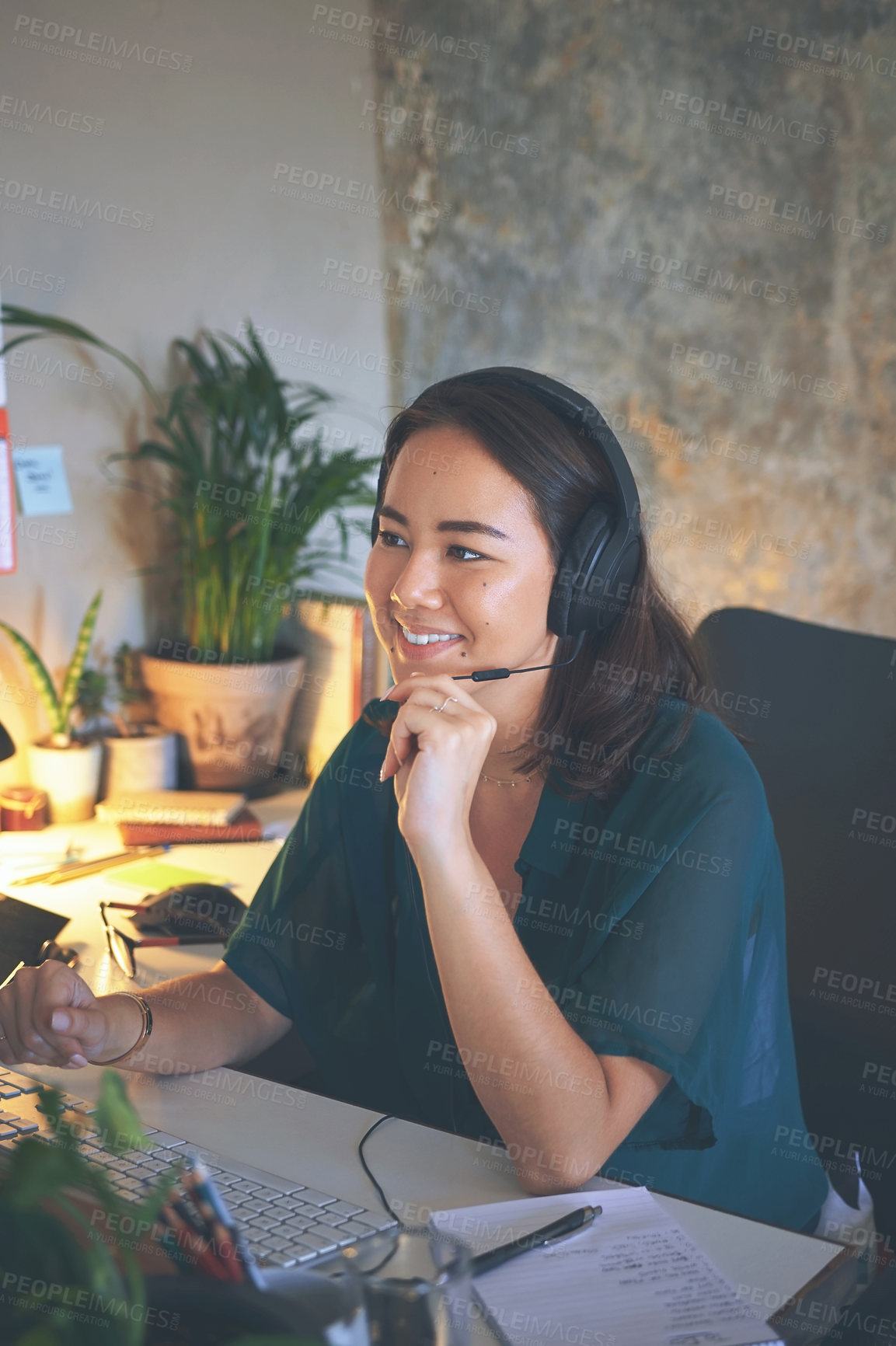 Buy stock photo Shot of an attractive young woman sitting alone and wearing a headset while working from home