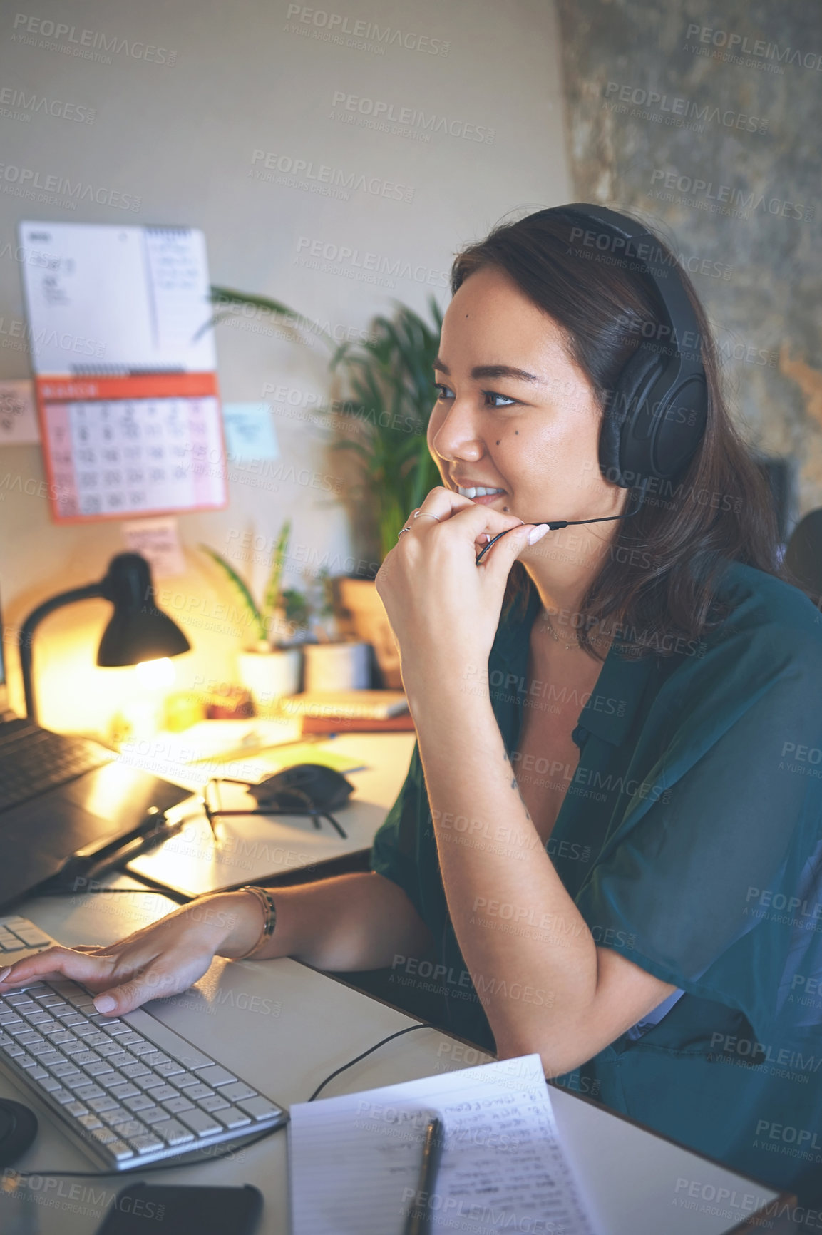 Buy stock photo Shot of an attractive young woman sitting alone and wearing a headset while working from home