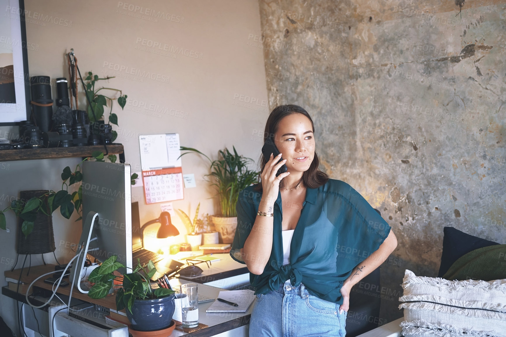 Buy stock photo Shot of an attractive young woman standing alone and using her cellphone to work from home