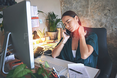 Buy stock photo Shot of an attractive young woman sitting alone and suffering from neck ache while working from home