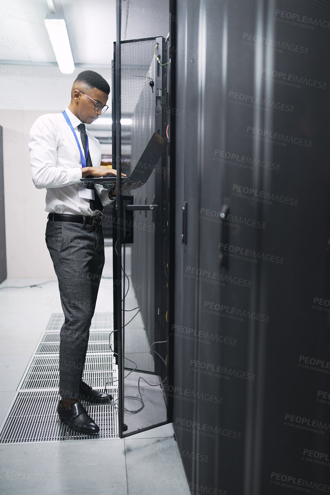 Buy stock photo Shot of a young male IT technician in a server room