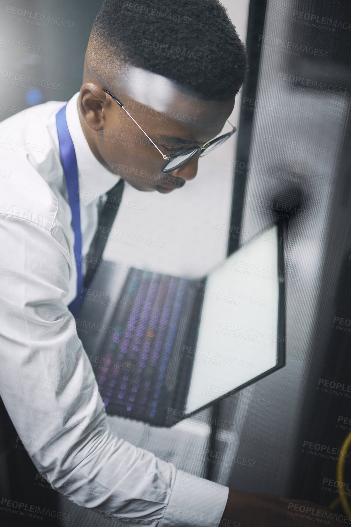 Buy stock photo Shot of a young male technician working in a server room