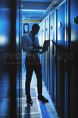 Buy stock photo Shot of a young man working in an IT server room