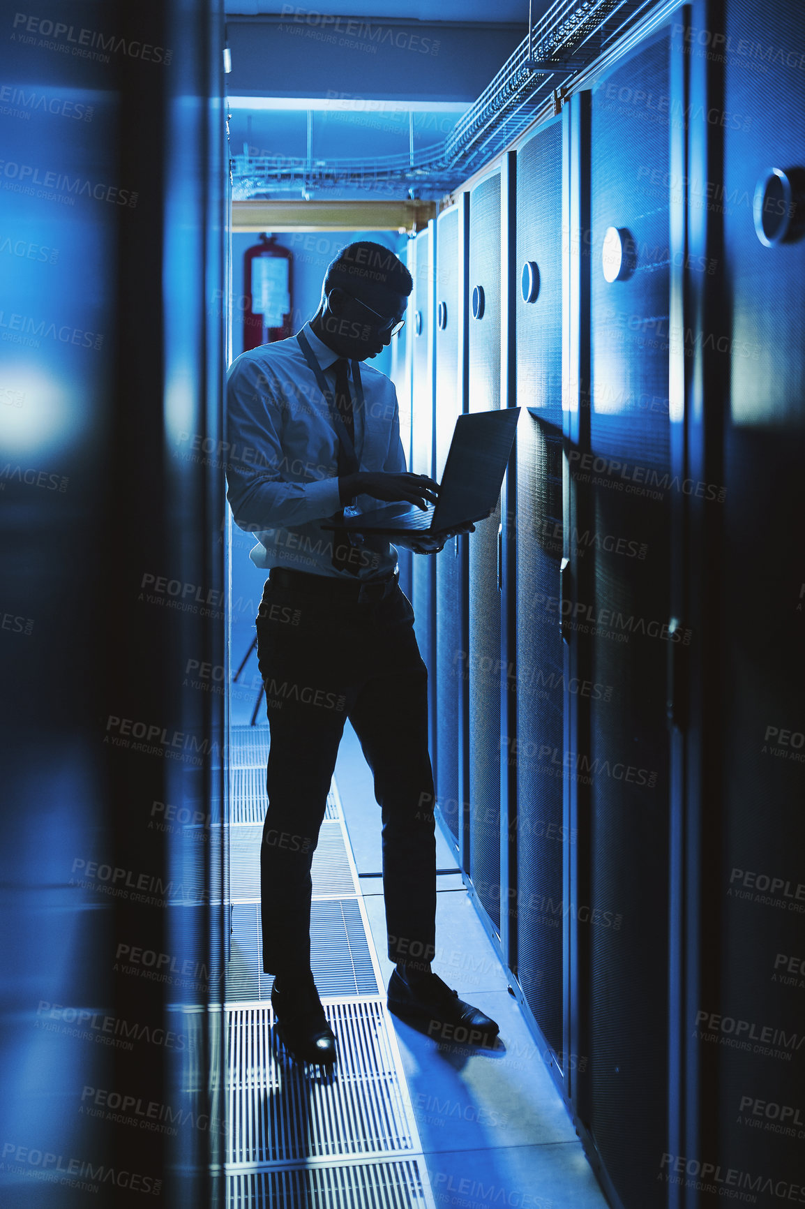 Buy stock photo Shot of a young man working in an IT server room