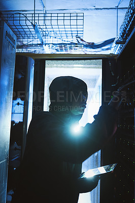 Buy stock photo Shot of a hacker using a digital tablet in a server room