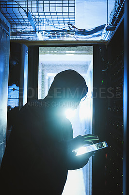 Buy stock photo Shot of a hacker using a digital tablet in a server room