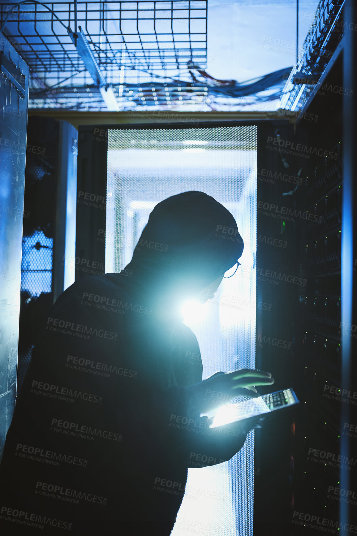 Buy stock photo Shot of a hacker using a digital tablet in a server room