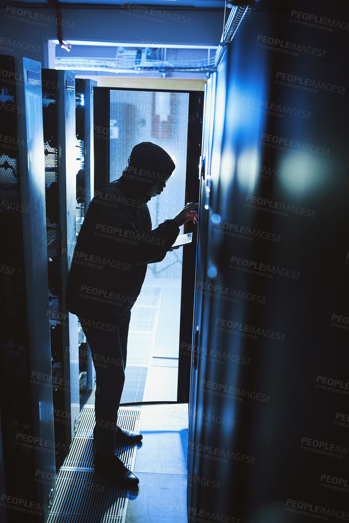 Buy stock photo Shot of a hacker using a digital tablet in a server room