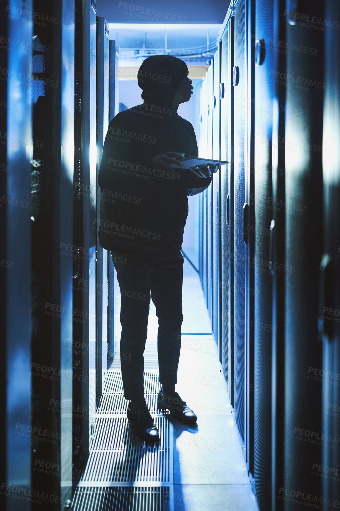 Buy stock photo Shot of a hacker using a digital tablet in a server room