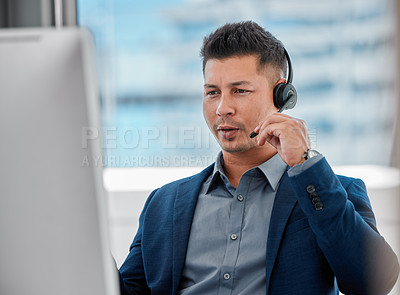 Buy stock photo Shot of a young man using a headset and computer
at work in a modern office
