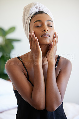 Buy stock photo Shot of a beautiful young woman applying moisturiser to her fave