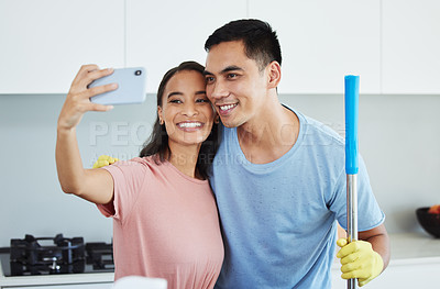Buy stock photo Shot of a couple taking a break from cleaning to take a selfie