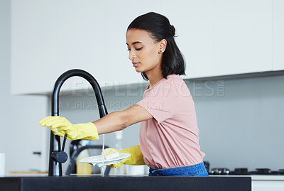 Buy stock photo Shot of a young woman washing dishes in her kitchen