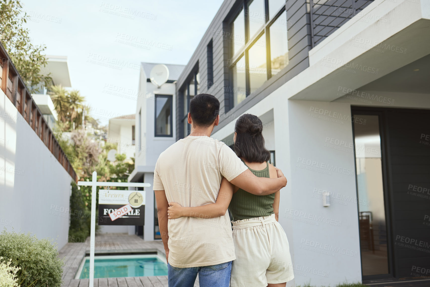 Buy stock photo Rearview shot of a young couple standing outside their new home