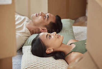 Buy stock photo Shot of a young couple lying on the floor in their new home