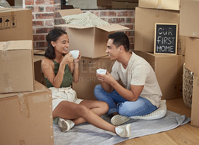 Buy stock photo Shot of a young couple drinking tea while surrounded by boxes in their new home