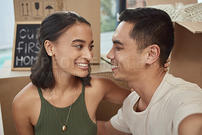 Buy stock photo Shot of a young couple sitting together in their new home
