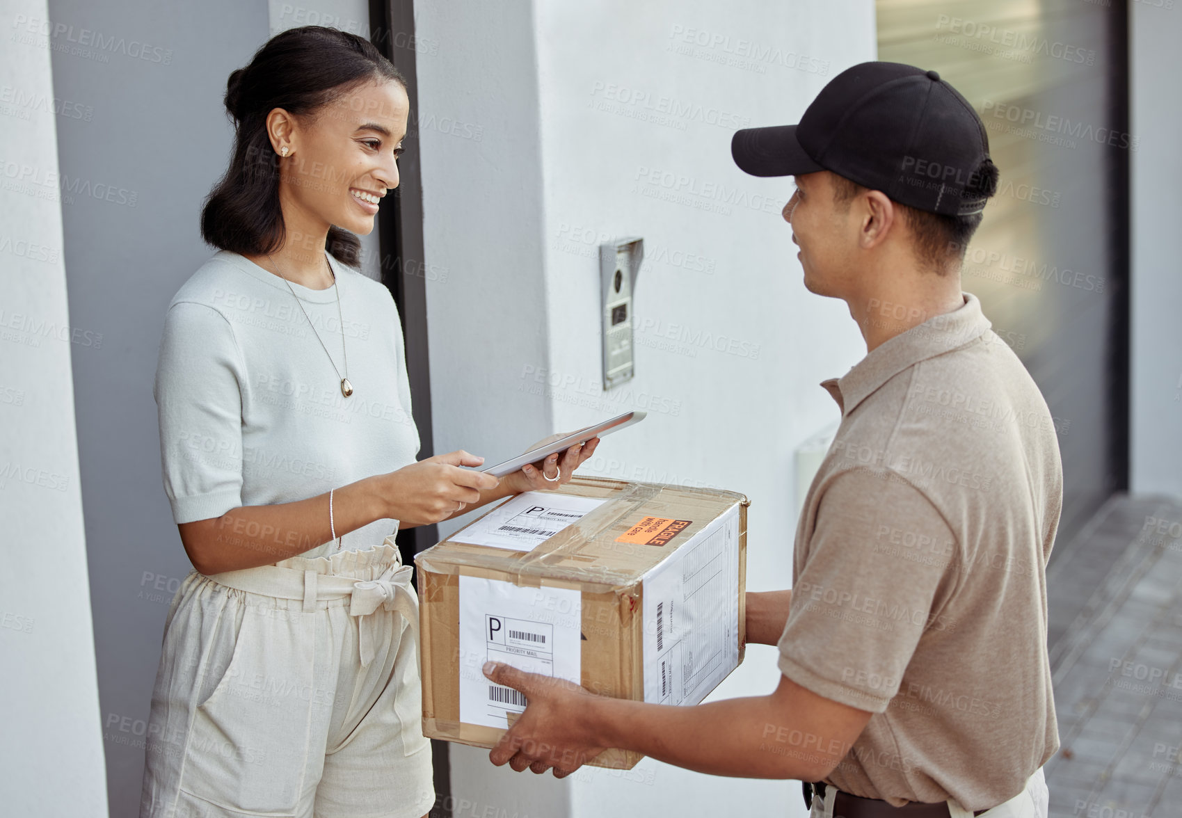 Buy stock photo Shot of a young woman signing for an order with a delivery man using a digital tablet