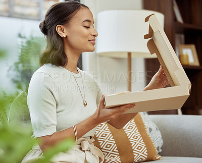 Buy stock photo Shot of a young woman sniffing her box of food in satisfaction