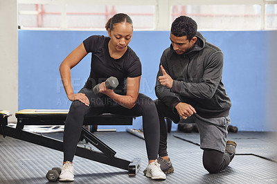 Buy stock photo Shot of a young woman exercising with a trainer at the gym