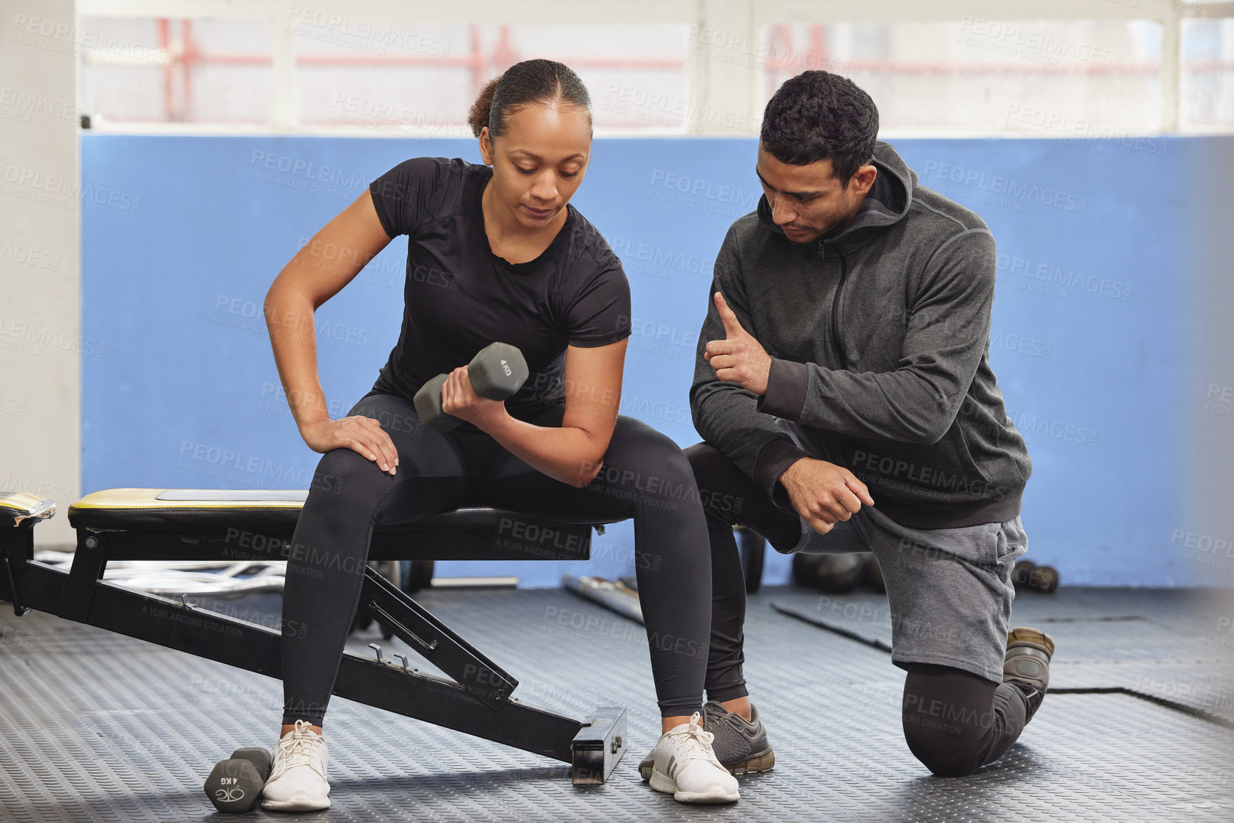 Buy stock photo Shot of a young woman exercising with a trainer at the gym